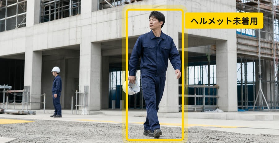 建設現場で、ヘルメットを手に持ったまま歩く作業者に「ヘルメット未着用」の検知枠が付いている